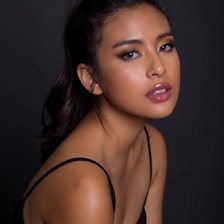 Close-up shot of a female pornstar smiling confidently against a dark background.