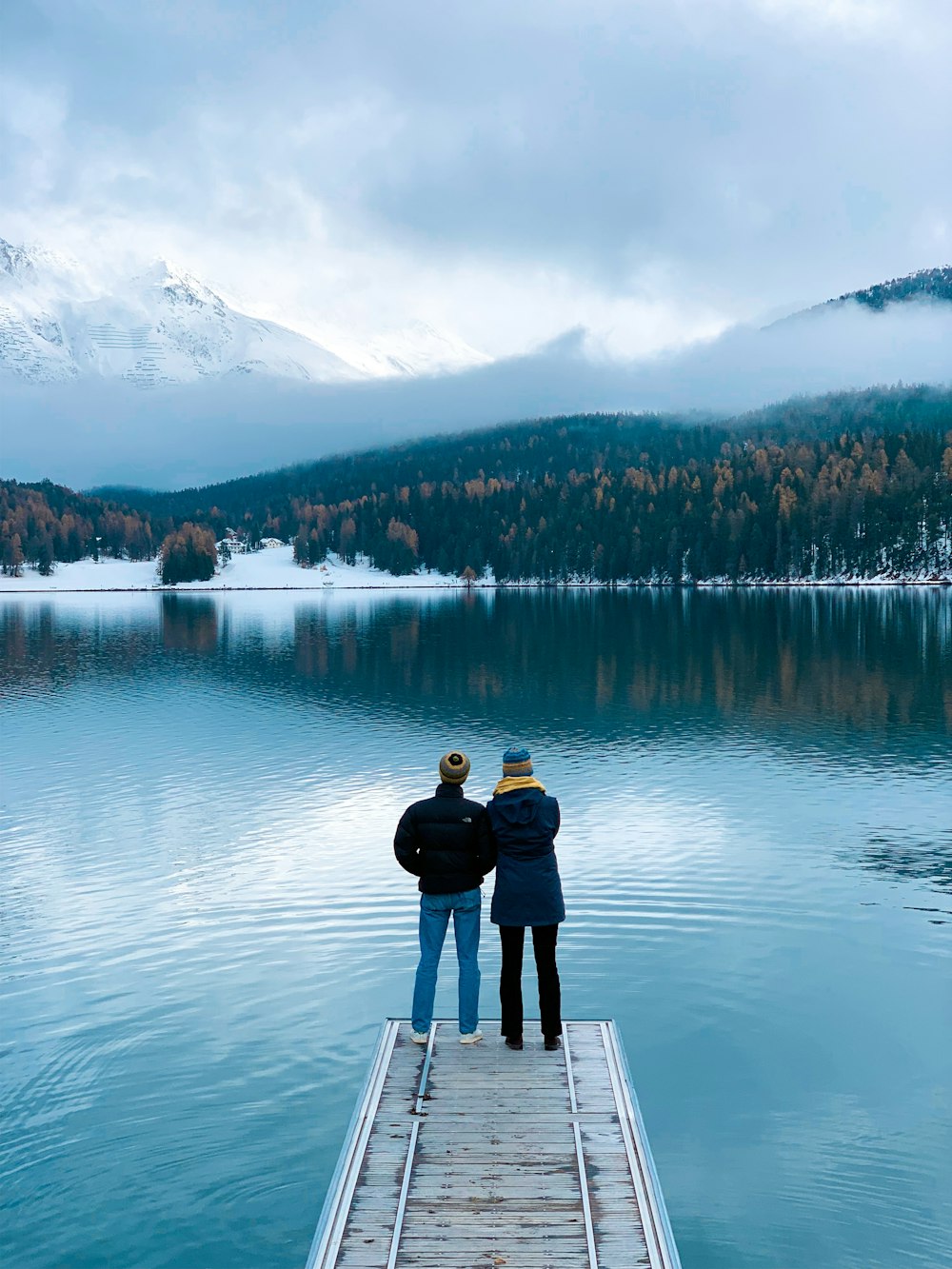 two persons standing on dock during daytime