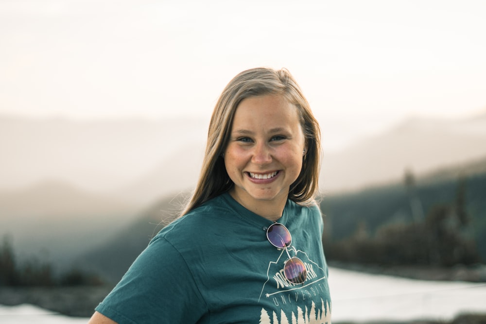 woman in shirt smiling near body of water