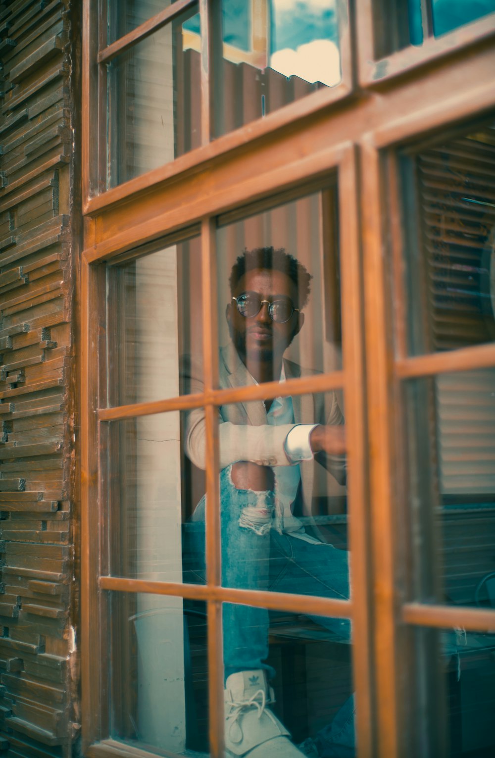 hombre sentado cerca de la ventana de cristal