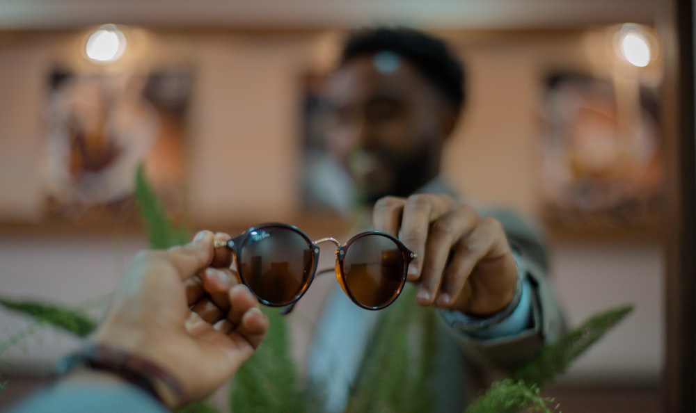 person holding black framed sunglasses close-up photography