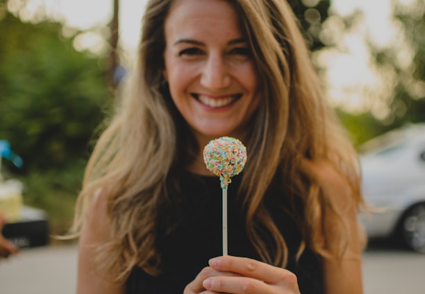 A smiling customer holding a beautifully decorated cake, surrounded by baking ingredients from Rise Baking Company.