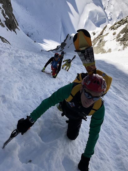A group of climbers ascending a snowy alpine peak with a guide leading the way.