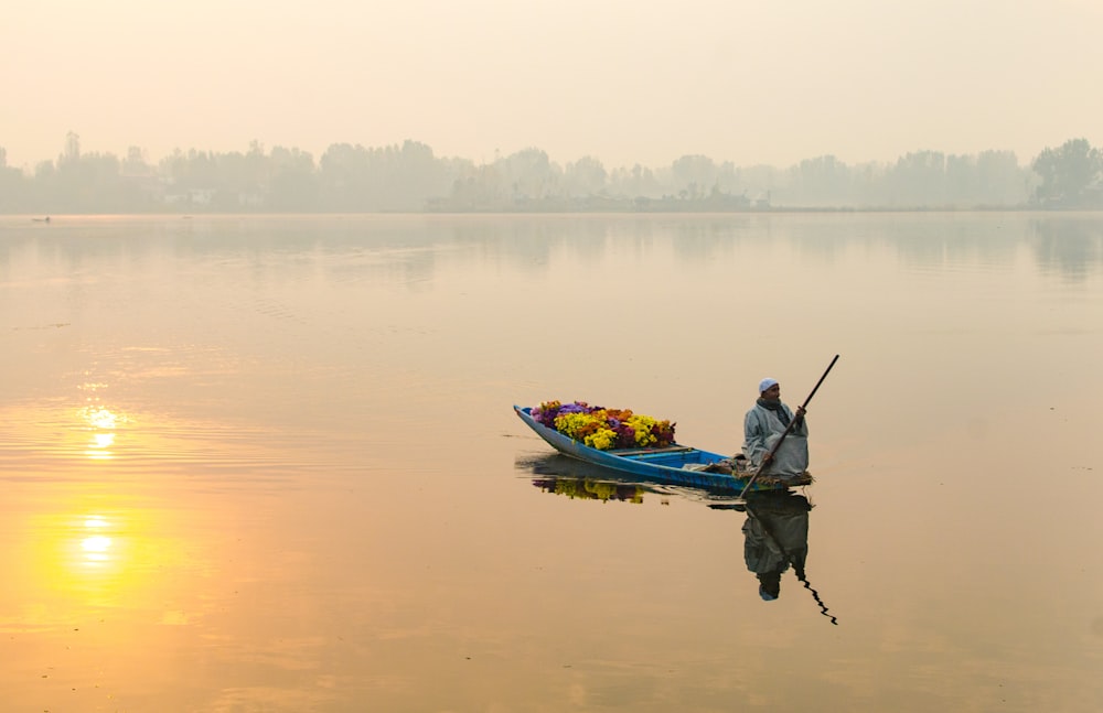 man on boat floating on calm body of water during golden hour