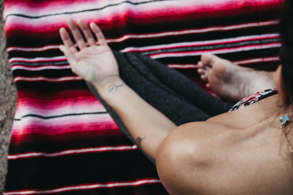 person sitting on red and black striped mat