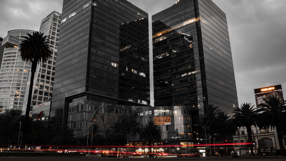grayscale photo of two glass buildings near road