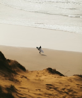 person walking while holding surfboard