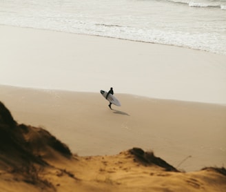 person walking while holding surfboard