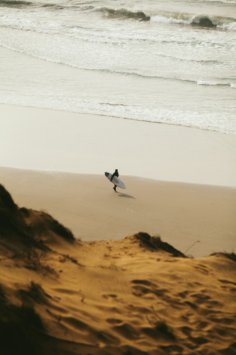 person walking while holding surfboard