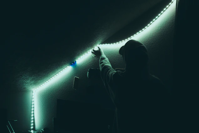 Electrician fixing home wiring with LED profile lighting installation in a cozy living room.