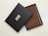 A brown leather wallet is partially visible inside an open black box. The box has a textured surface with the letters 'RVI' embossed in white. The wallet features multiple card slots and appears to be of high quality.