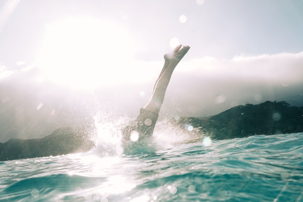 person diving on body of water during daytime