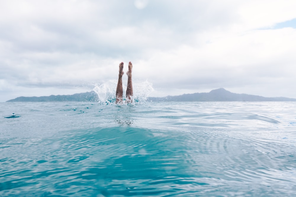 person diving on body of water during daytime