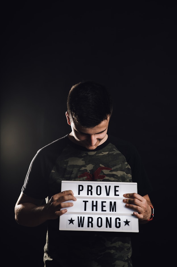man holding white prove them wrong signage