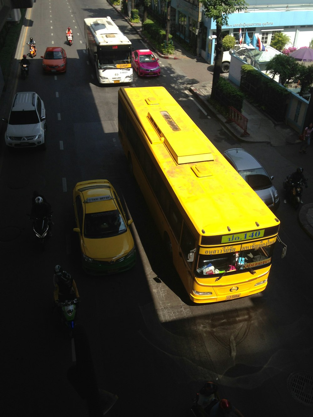 yellow bus beside taxi on the road