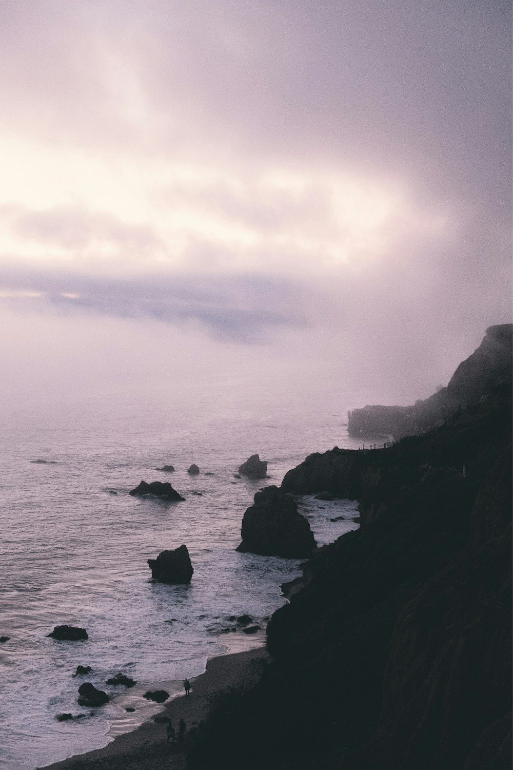 rock formations near sea during foggy weather