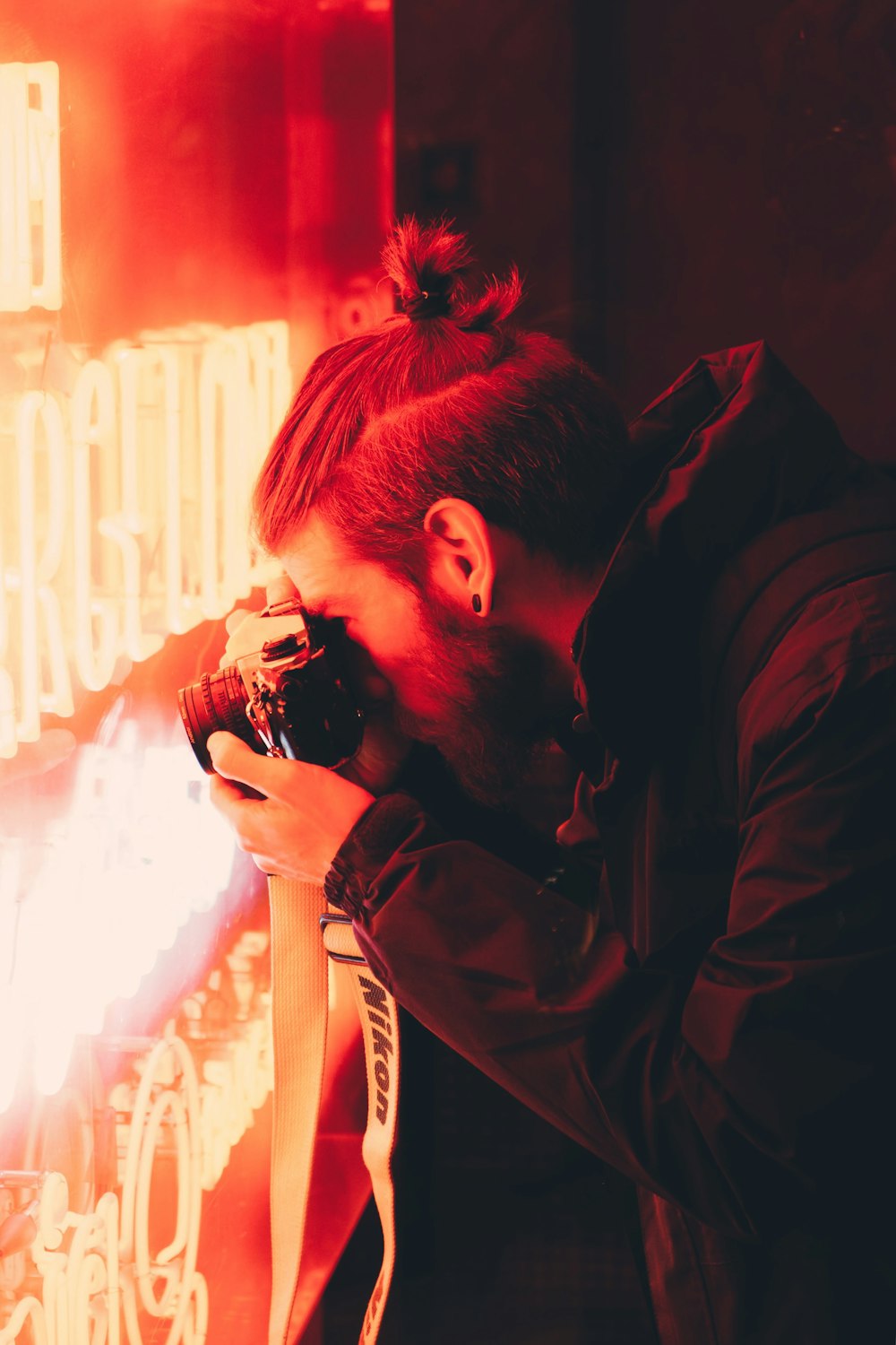 man taking photo of red LED neon signage