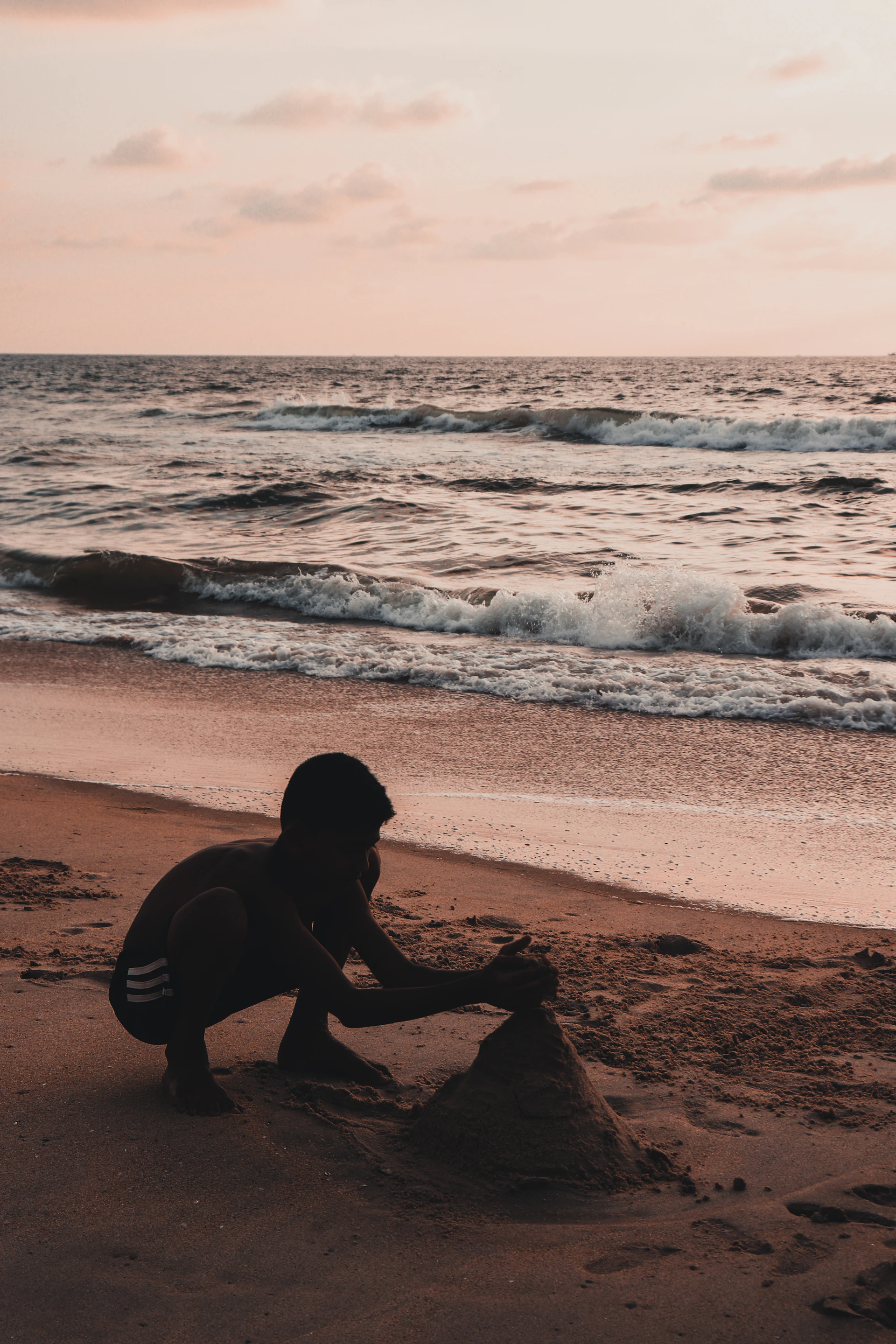 A candid moment of siblings building a sandcastle together on a sunny beach day.