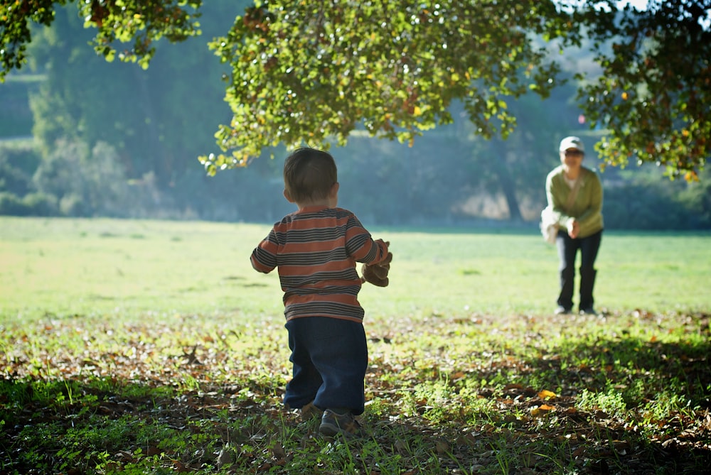 focus photography of boy standing near tree