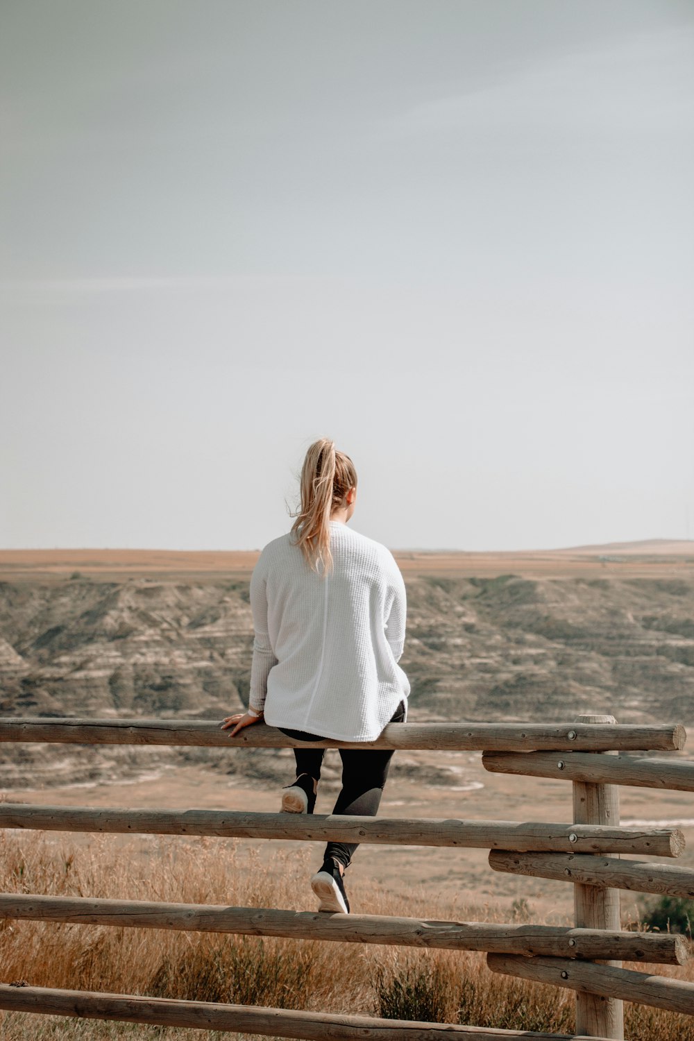 woman sitting on brown wooden railings