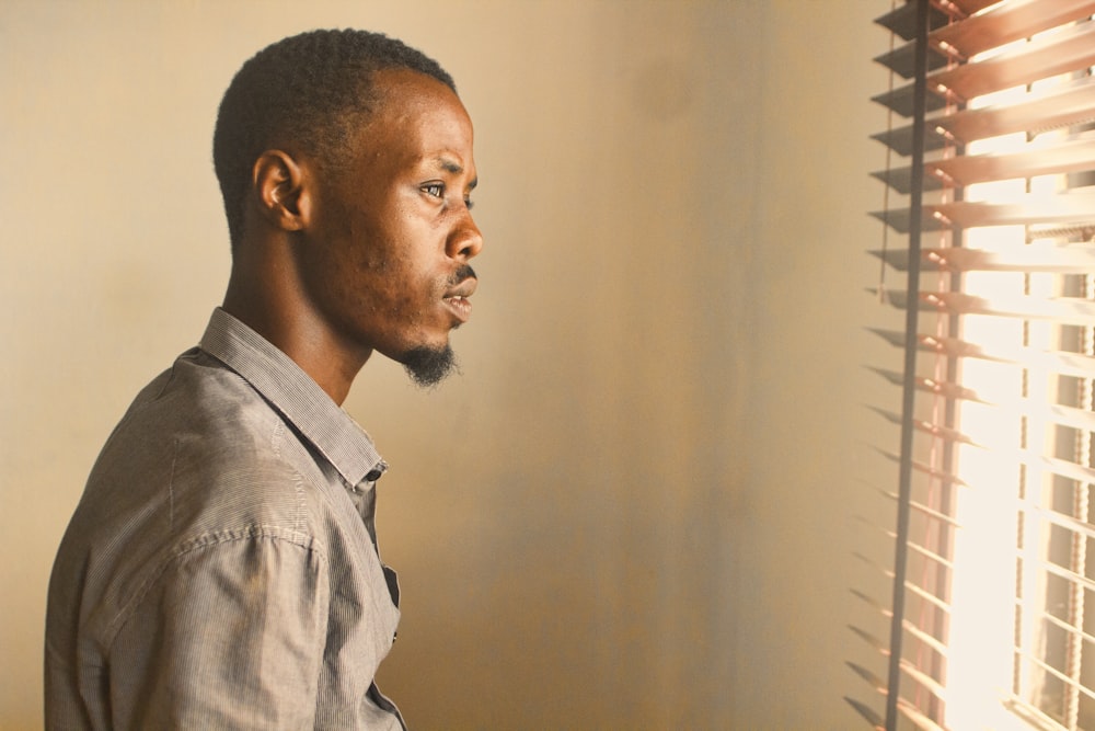 man standing near window with blinds