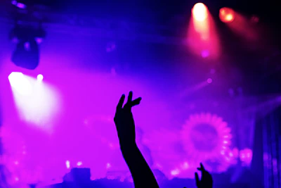 Vivid crowd silhouette against industrial architecture soaked in vibrant rave colors.