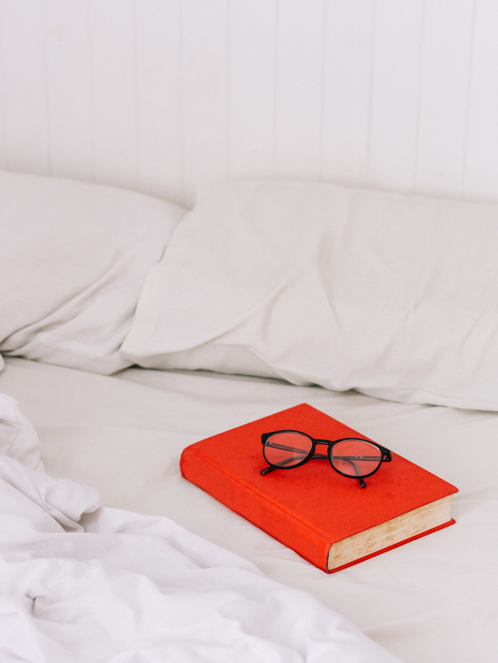 Brillen mit schwarzem Rahmen auf orangefarbenem Buch