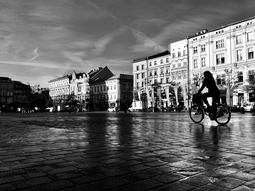 grayscale photography of woman on bike in city