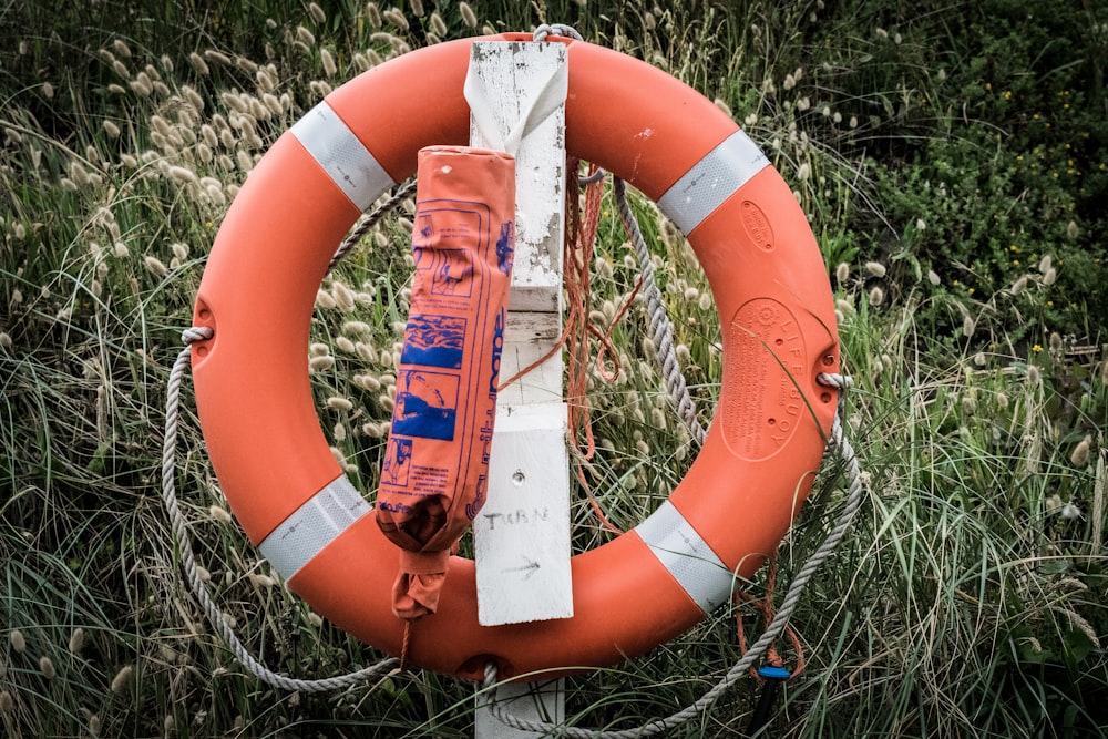 orange life saver hanging on white wooden post