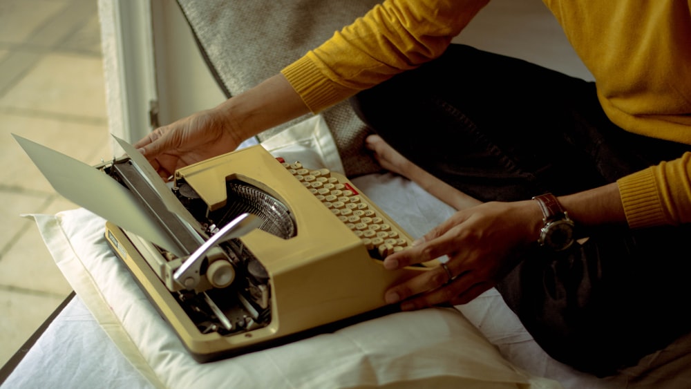 pessoa usando máquina de escrever amarela