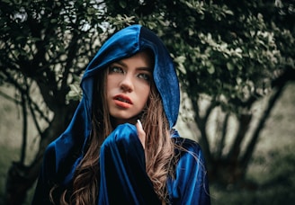 A model draped in a hooded cloak that shifts colors subtly in a smoky atmosphere.