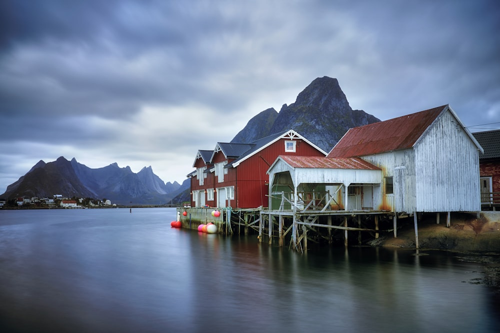 red and white wooden houses near mountains and facing body of water