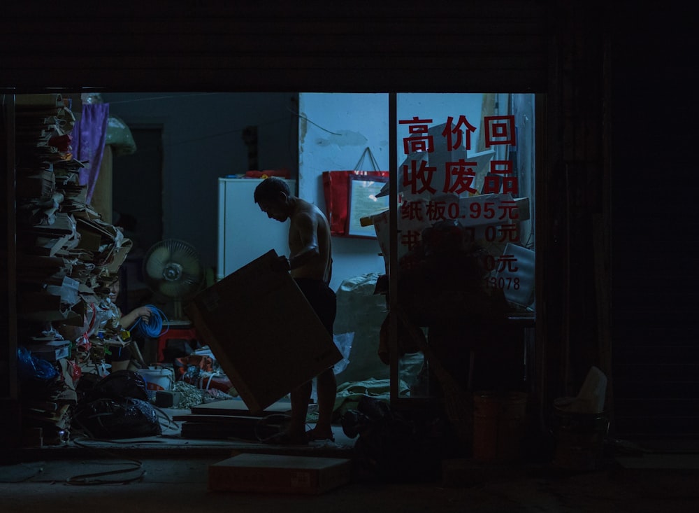 man holding wooden panel inside storage room