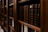 Close-up of a middle-aged man browsing books on a vintage wooden shelf at home.