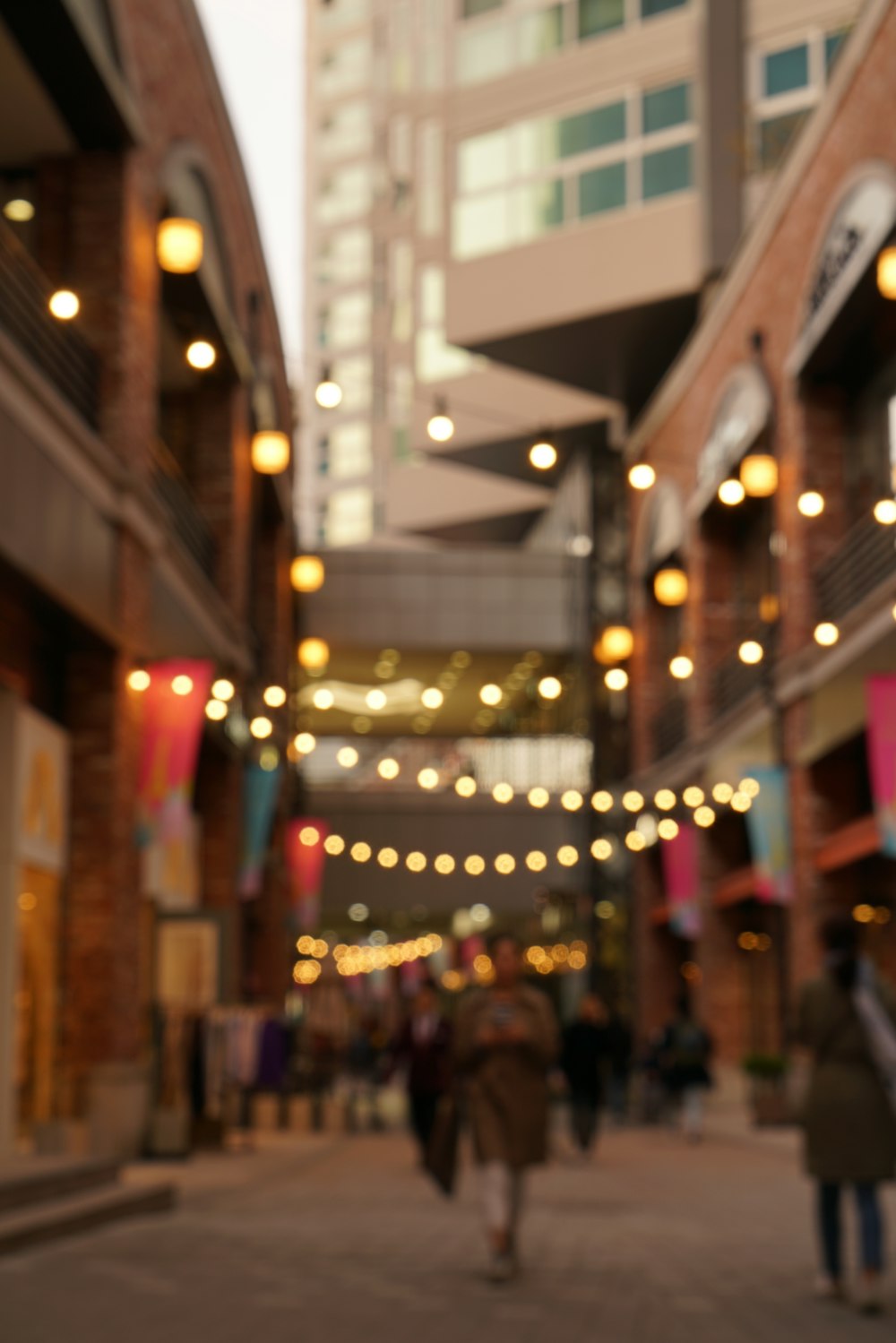 people walking in the streets with strings lights above