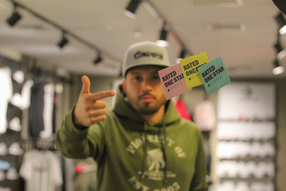 man in pullover hoodie and cap pointing at rated one star notes