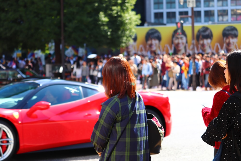 people standing near red vehicle