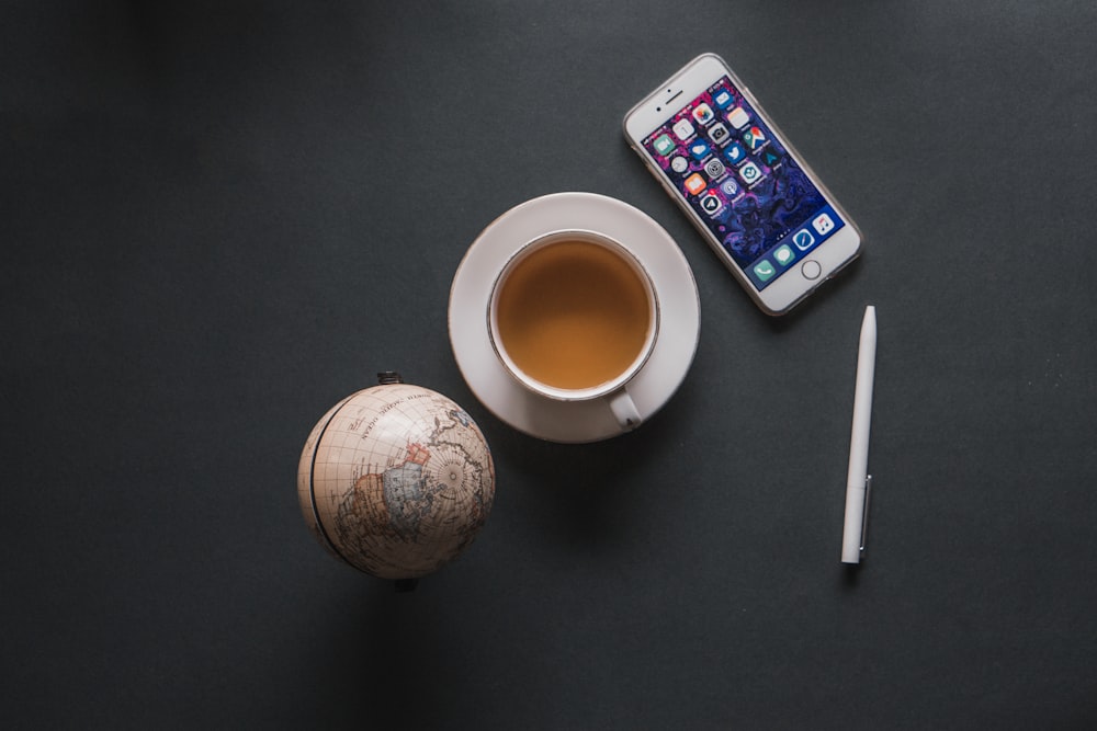 iPhone beside white ceramic cup with saucer