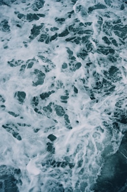 Aerial view of ocean waves creating intricate patterns of foam and swirling water.