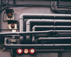 A photo of clean metallic pipes running into a building.