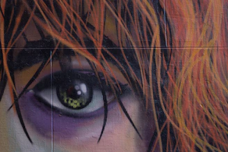 Close-up of an intense anime eye with glowing red highlights.