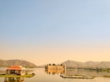 A serene lake reflecting historic palaces under a clear sky.