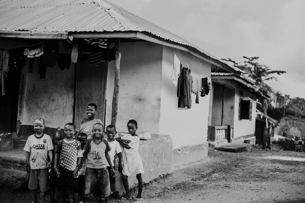 grayscale photo of kids outside house