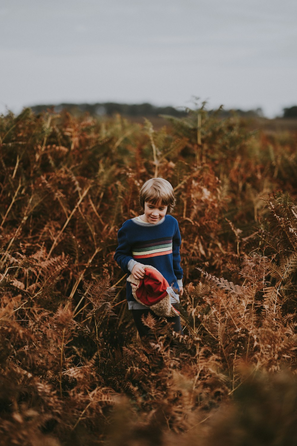 selective focus photography of boy standing surrounded by plants
