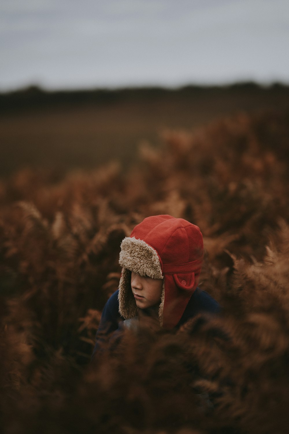 boy wearing red hat in brown field