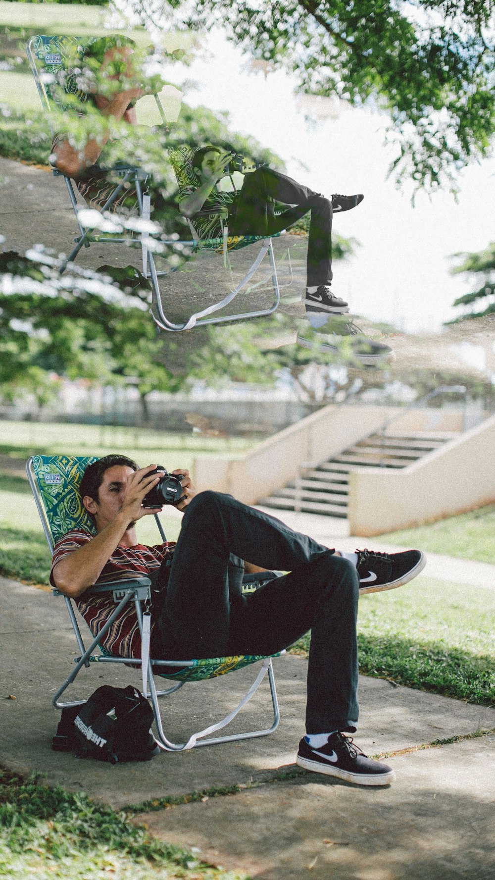 man sitting on folding chair using DSLR camera