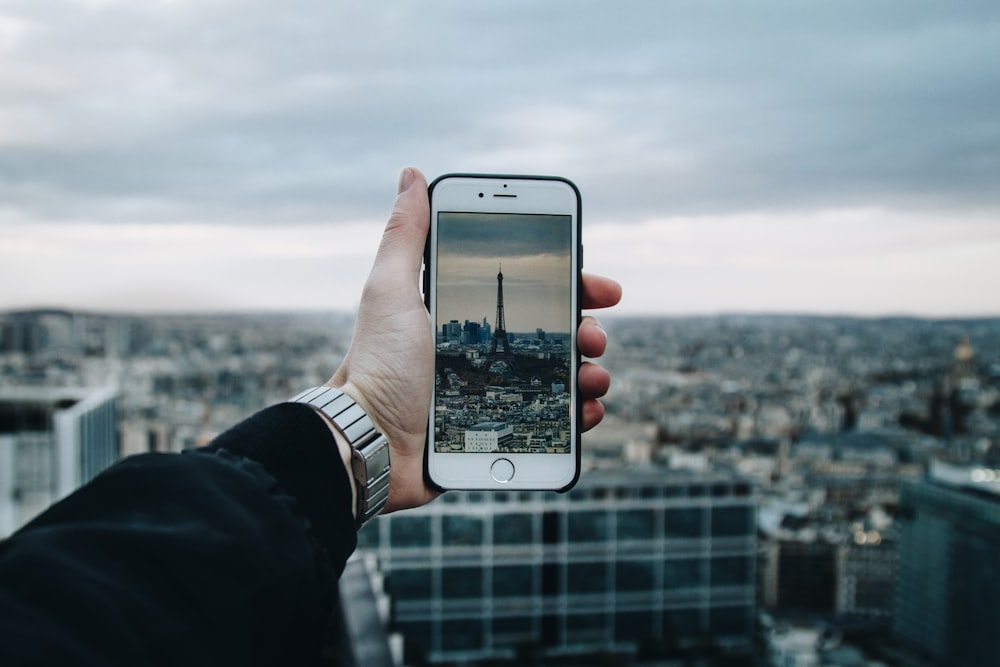 personne tenant un iPhone 6 argenté avec une coque noire