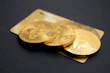 three round gold-colored Bitcoin tokens