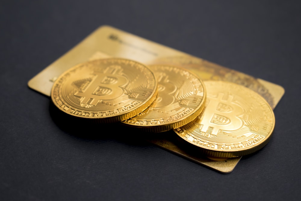 three round gold-colored Bitcoin tokens