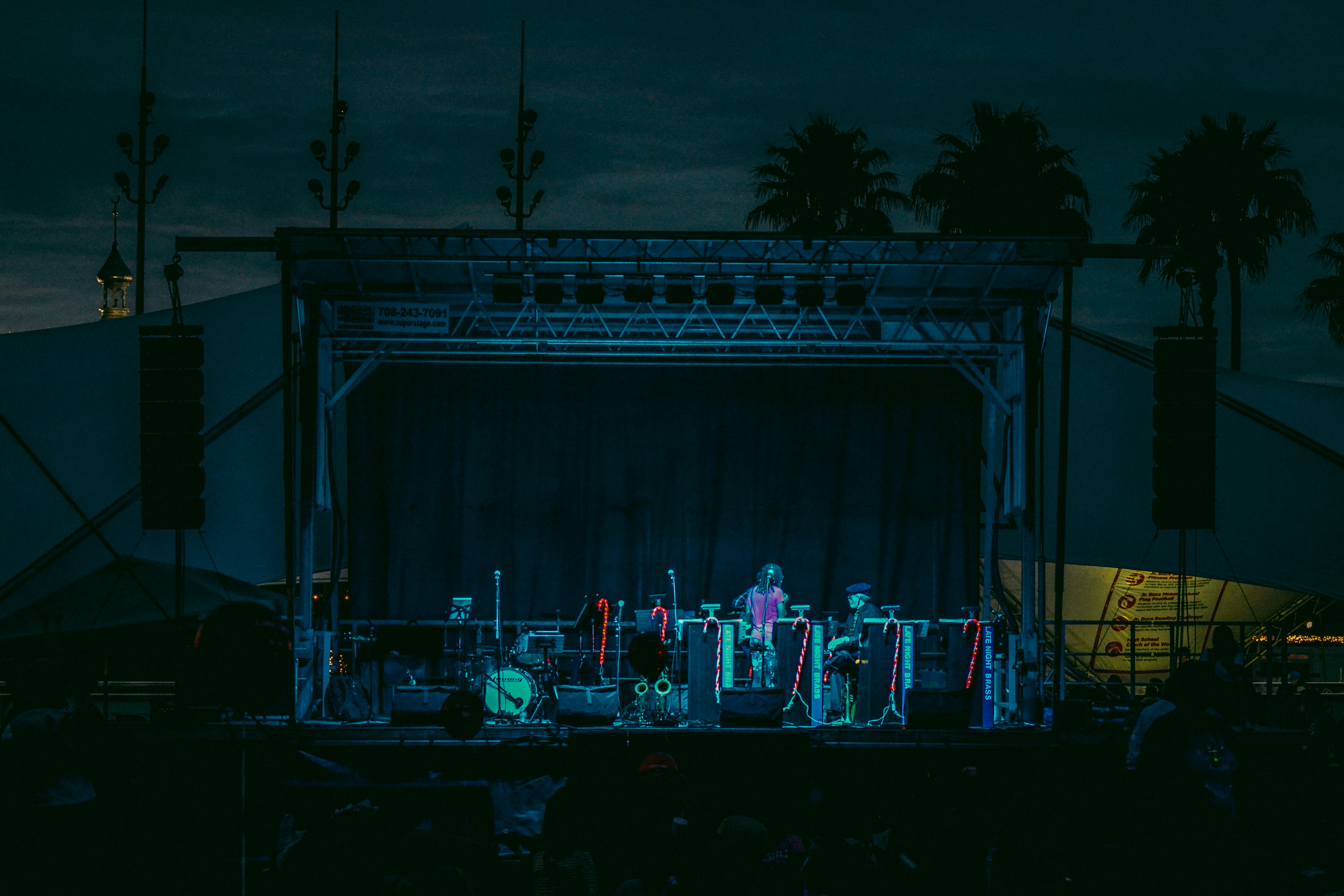 Banda cubana actuando con percusión e instrumentos de viento bajo dramática iluminación de escenario por la noche